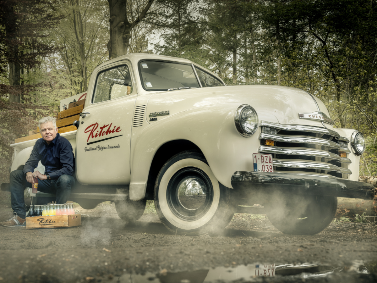 Ondernemer Jan Verlinden poseert bij een promo-oldtimer met Ritchiebedrukking.